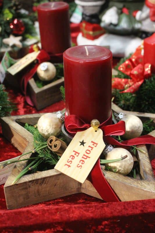 Holzstern mit Weihnachtsdeko und roter Kerze